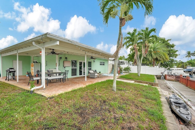 back of property featuring ceiling fan, a patio area, and a lawn