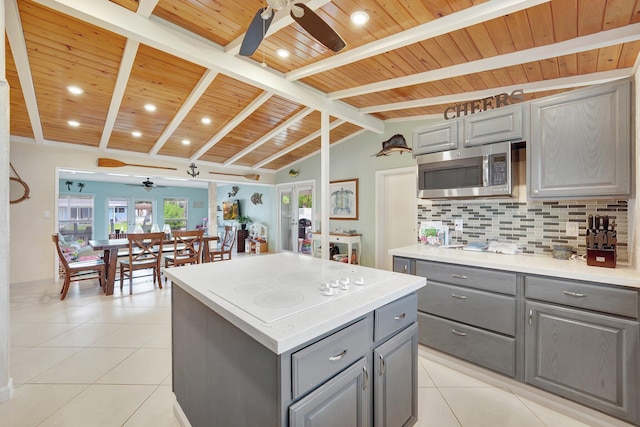 kitchen featuring light tile patterned flooring, decorative backsplash, a kitchen island, and gray cabinetry