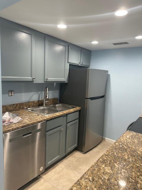 kitchen featuring appliances with stainless steel finishes, sink, gray cabinetry, and dark stone counters