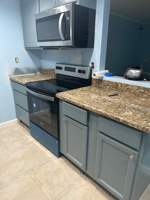 kitchen featuring stainless steel appliances, gray cabinets, and dark stone counters