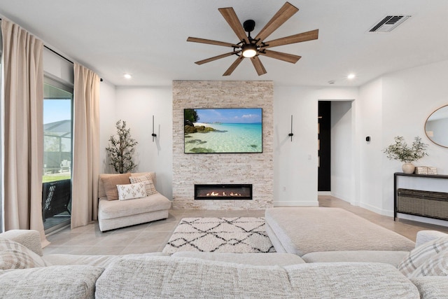 living room featuring light tile patterned flooring, ceiling fan, and a stone fireplace