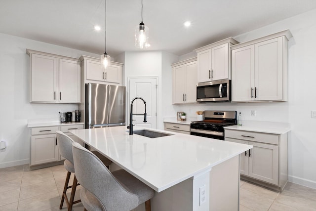 kitchen with pendant lighting, appliances with stainless steel finishes, sink, and a kitchen island with sink