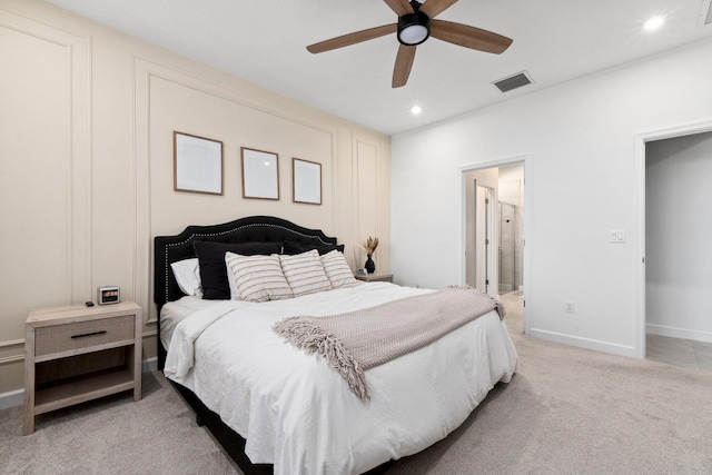 bedroom featuring ceiling fan, ensuite bath, and light carpet