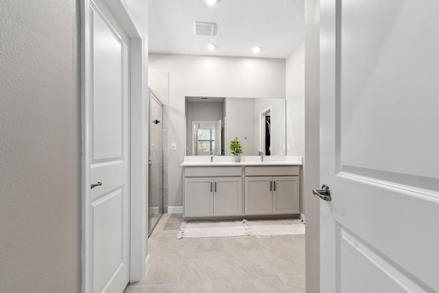 bathroom with vanity, a textured ceiling, and a shower with shower door