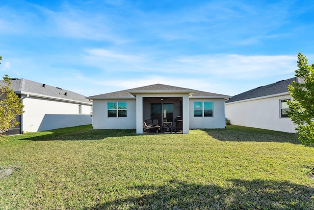 rear view of property featuring a lawn and ceiling fan