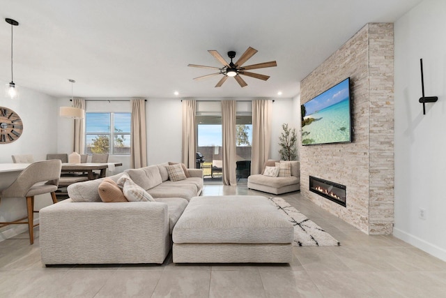 living room with ceiling fan and a stone fireplace