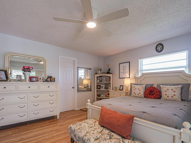 bedroom featuring a textured ceiling, ceiling fan, and light wood-type flooring