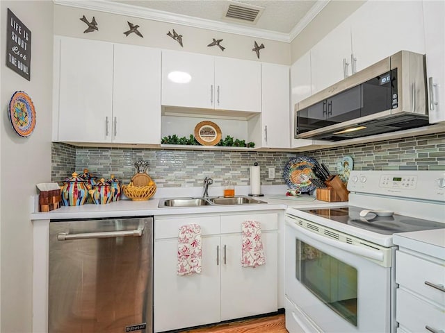 kitchen with white cabinetry, appliances with stainless steel finishes, crown molding, and decorative backsplash