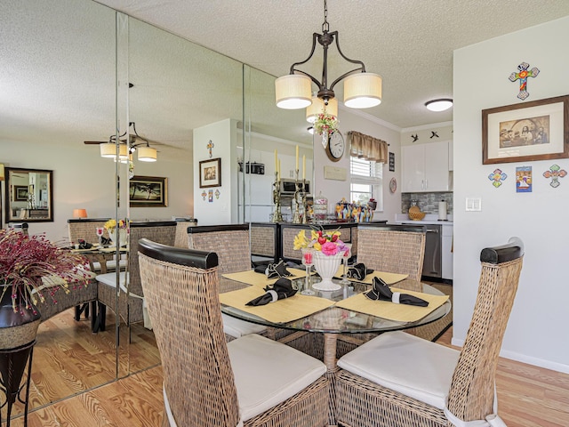 dining room with a chandelier, a textured ceiling, and light wood-type flooring