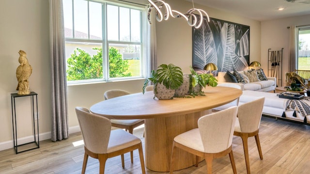 dining space with an inviting chandelier, a wealth of natural light, and light wood-type flooring