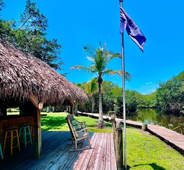 wooden deck with a gazebo, a water view, a yard, and a bar