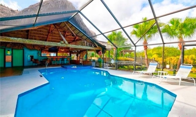 view of swimming pool with a bar, glass enclosure, and a patio