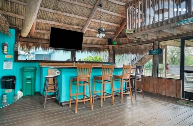 bar with hardwood / wood-style floors and ceiling fan