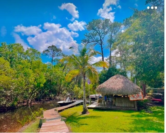 view of home's community with a gazebo, a dock, and a lawn