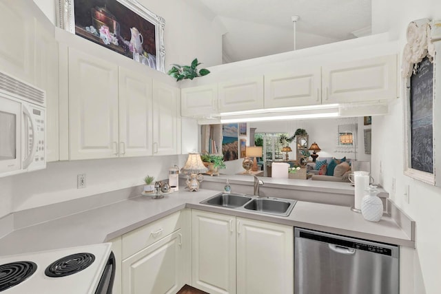 kitchen with white appliances, kitchen peninsula, sink, and white cabinets