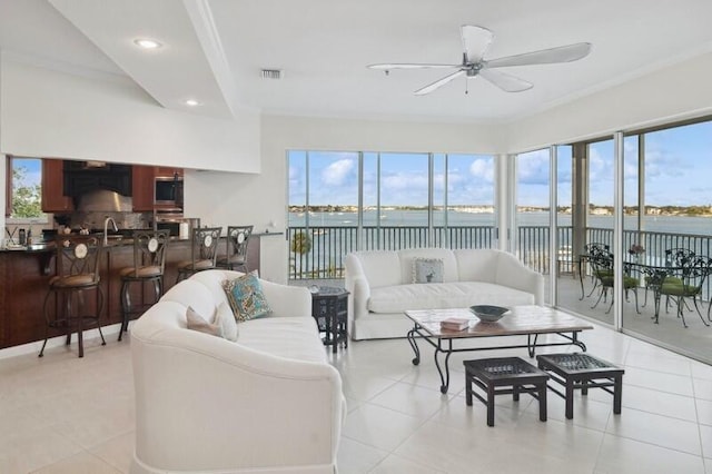 tiled living room featuring ornamental molding, a water view, and ceiling fan