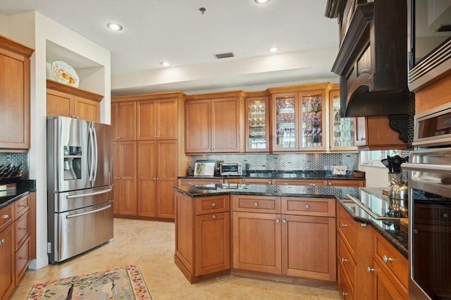 kitchen with backsplash, stainless steel appliances, and dark stone counters