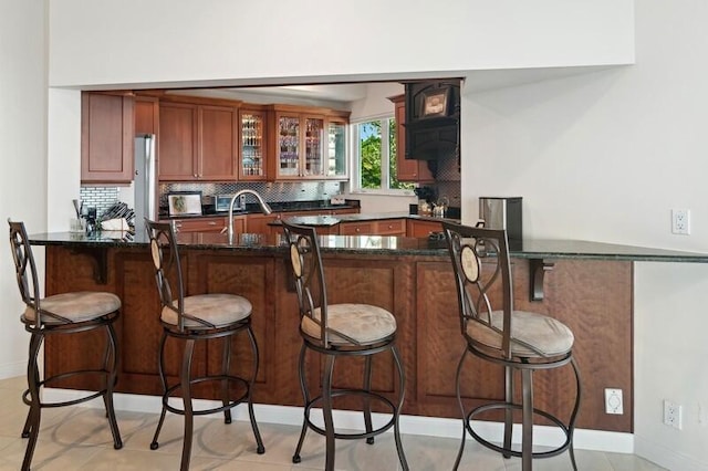 bar featuring tasteful backsplash, sink, and dark stone countertops