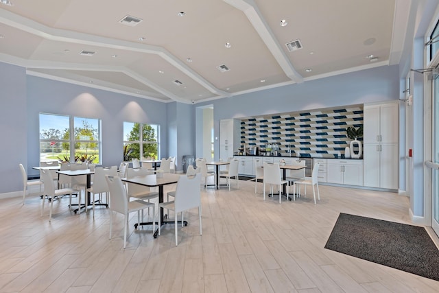 dining area with crown molding, high vaulted ceiling, and light hardwood / wood-style floors