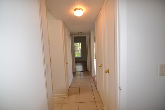 hallway featuring a textured ceiling and light tile patterned floors