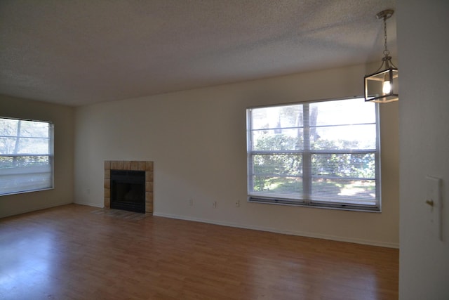 unfurnished living room featuring a textured ceiling, a tile fireplace, and hardwood / wood-style flooring