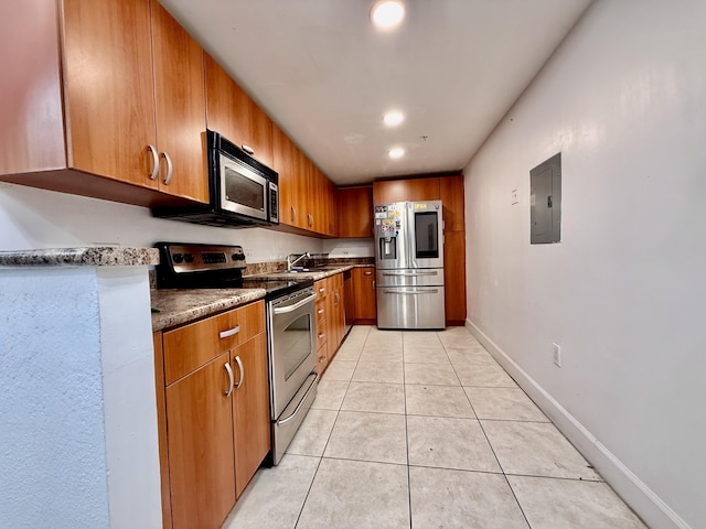 kitchen with brown cabinetry, stainless steel appliances, light tile patterned floors, electric panel, and a sink