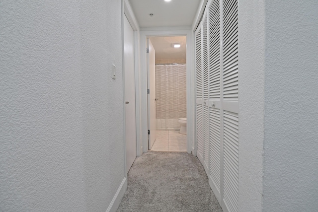 hall with tile patterned floors, carpet, and a textured wall