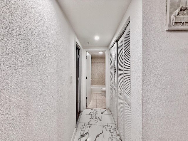 hallway with recessed lighting, a textured wall, and marble finish floor