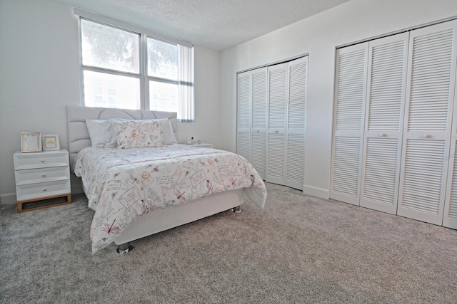 carpeted bedroom with a textured ceiling and two closets