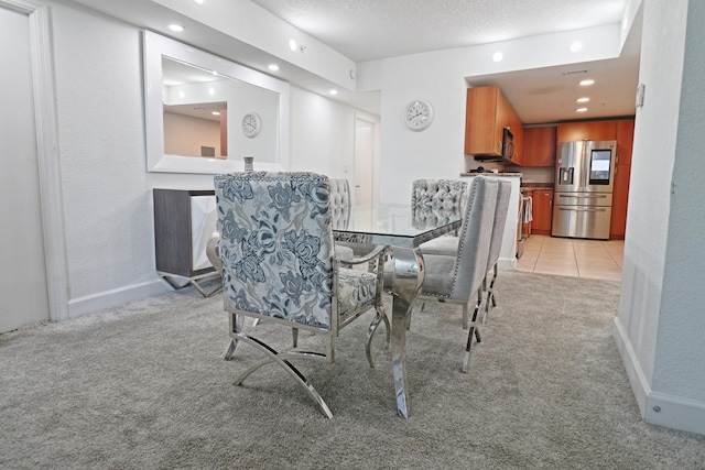 dining space with light colored carpet and a textured ceiling