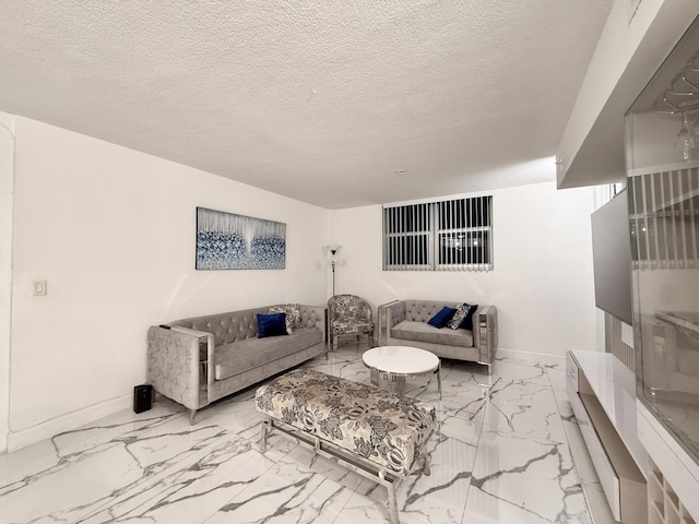 living room featuring marble finish floor, a textured ceiling, and baseboards