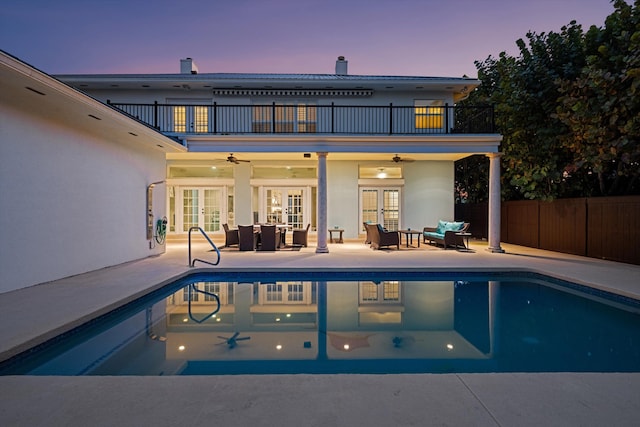 401 Center St, Jupiter, FL 33458 - back of property at dusk featuring french doors, a balcony, ceiling fan, and a chimney