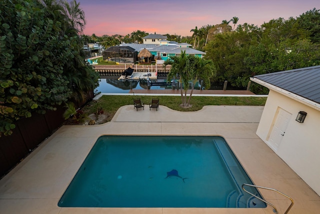 401 Center St, Jupiter, FL 33458 - pool at dusk featuring a patio area, a water view, an outdoor pool, and a boat dock