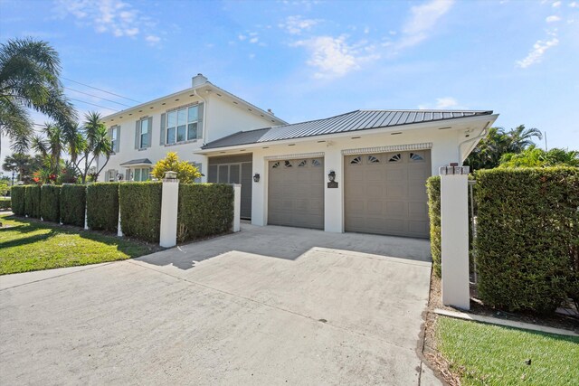 401 Center St, Jupiter, FL 33458 - view of front of house with stucco siding, concrete driveway, an attached garage, and metal roof
