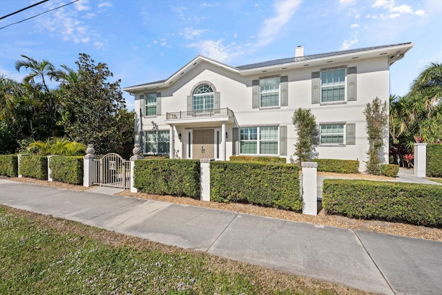 401 Center St, Jupiter, FL 33458 - view of front facade with a balcony, a gate, a fenced front yard, stucco siding, and a chimney