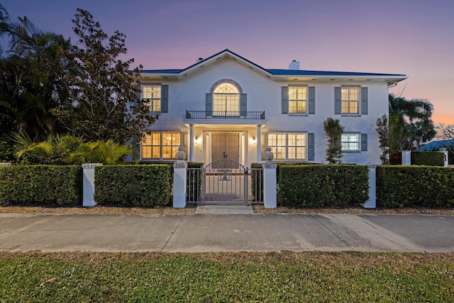 401 Center St, Jupiter, FL 33458 - colonial home featuring a balcony, a fenced front yard, a gate, stucco siding, and a chimney