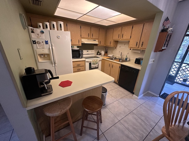 kitchen with sink, light tile patterned floors, a breakfast bar, and black appliances