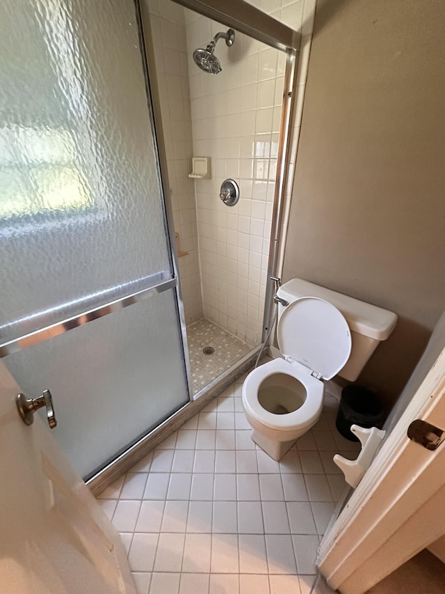 bathroom with tile patterned flooring, a shower with shower door, and toilet