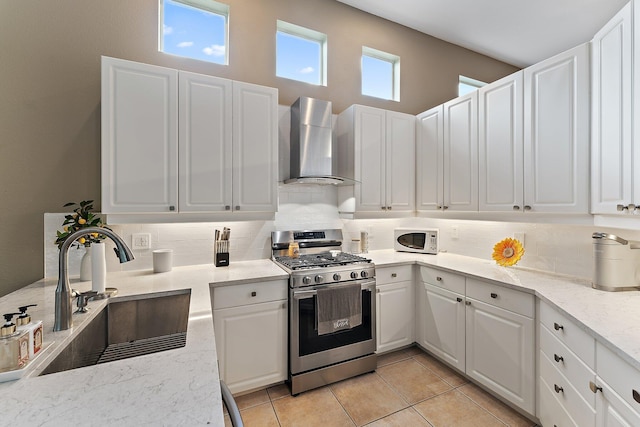 kitchen with white cabinetry, stainless steel gas range oven, sink, and wall chimney exhaust hood