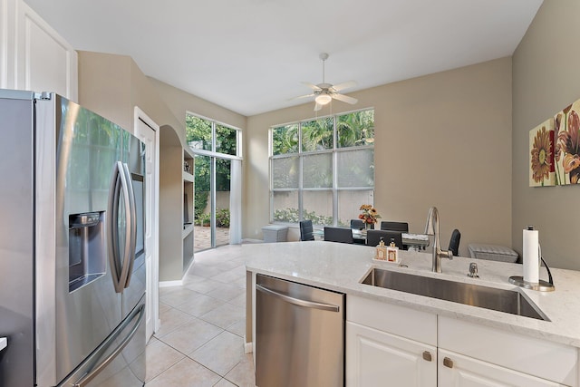 kitchen with sink, white cabinetry, stainless steel appliances, light stone countertops, and light tile patterned flooring