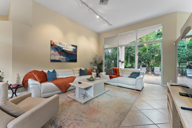 tiled living room with a towering ceiling and rail lighting