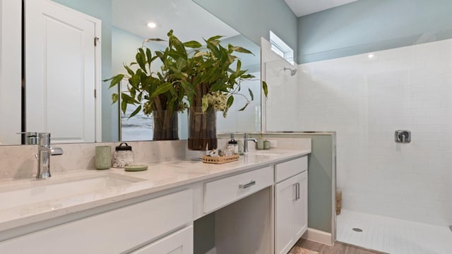 bathroom featuring tiled shower and vanity