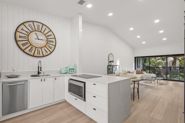 kitchen featuring appliances with stainless steel finishes, white cabinetry, sink, kitchen peninsula, and light hardwood / wood-style flooring