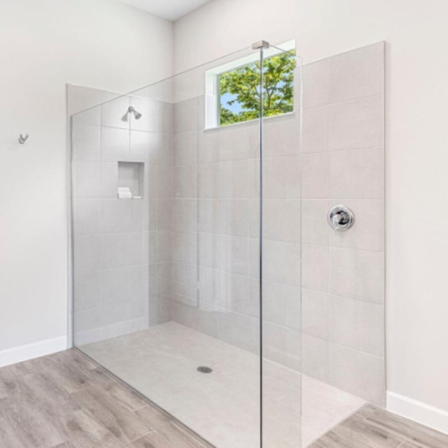 bathroom featuring hardwood / wood-style flooring and a tile shower