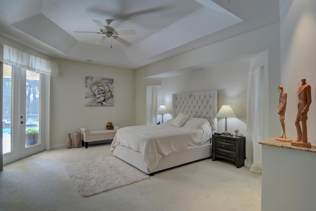 carpeted bedroom featuring french doors, ceiling fan, a tray ceiling, and access to outside