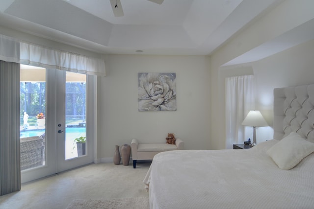 carpeted bedroom featuring french doors, ceiling fan, a tray ceiling, and access to exterior