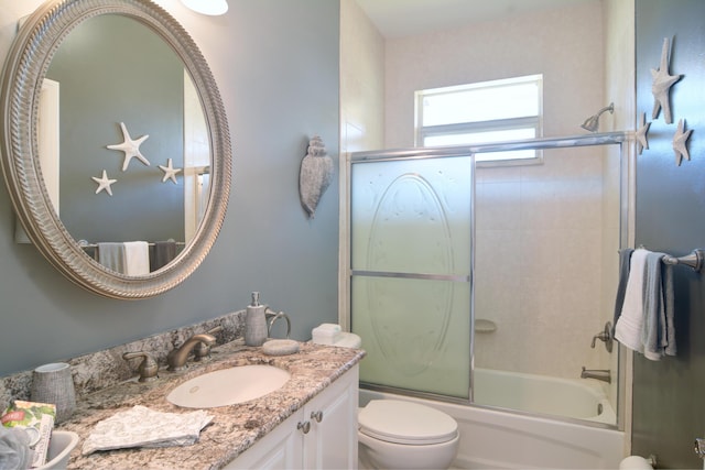 full bathroom featuring vanity, combined bath / shower with glass door, and toilet