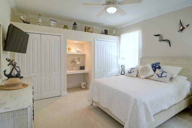 bedroom with crown molding, light colored carpet, ceiling fan, and two closets