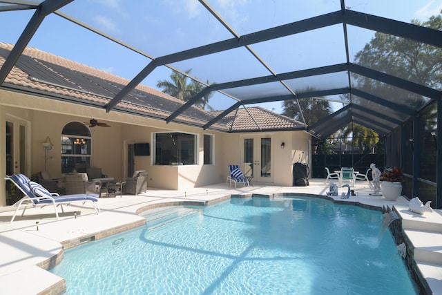 view of pool with ceiling fan, a patio, glass enclosure, french doors, and pool water feature