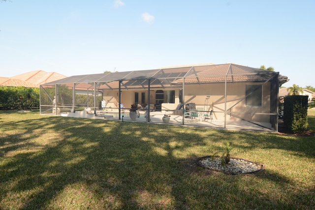 rear view of property featuring a yard, glass enclosure, and a patio area